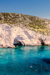 Fototapeta na wymiar Crystal clear water in front of a cave with people swimming at Porto Limnionas