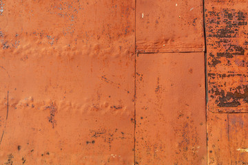Metallic rusty orange wall with peeling paint. Background texture