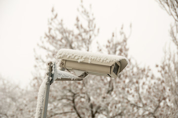 Outdoor security camera at the street in a winter. Surveillance camera against winter town..CCTV camera for the safety. Monitoring security camera. Electronic device.