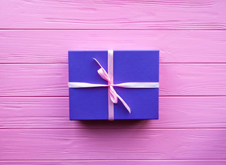 Purple gift box with pink ribbon on pink background.Christmas and other holidays concept. Top view,...