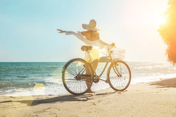 Happiness woman traveler with her bicycle rides on sea coastline