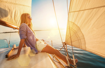 Young happy woman enjoying sunset from deck of sailing boat movi