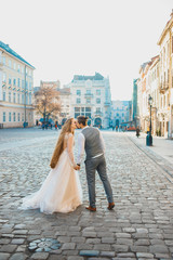 Young couple kissing on the background of the morning city. Lovely bride with long hair. Handsome...