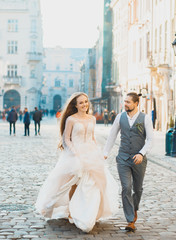 Amazing young couple on the background of the morning city. Lovely bride with long hair. Handsome...