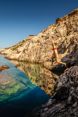 Girl jumping in the water at Korakonissi on a summer morning