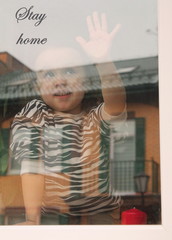 A little girl behind the glass in the house, looking at the street. Quarantine or self-isolation due to the Covid-19 pandemic. Stay at home