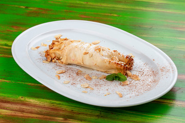 Apple strudel with peanuts. On a colored wooden background. Vegetarian dish.