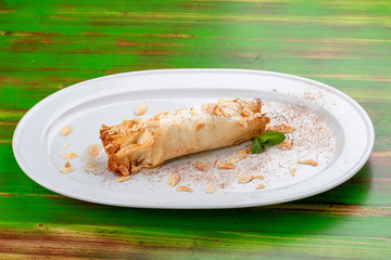 Apple strudel with peanuts. On a colored wooden background. Vegetarian dish.