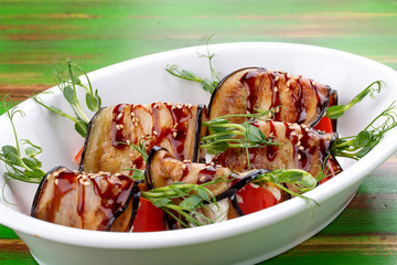 Eggplant vegetable rolls with unagi sauce. On a colored wooden background. Vegetarian dish.