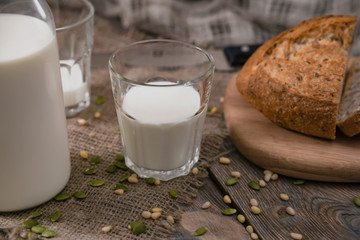 Milk and bread on wooden table with sackcloth. Rustic breakfast on Milk Day. Horizontal shot from above.