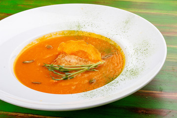 Pumpkin cream soup with tofu. On a colored wooden background. Vegetarian dish.