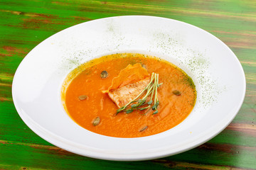 Pumpkin cream soup with tofu. On a colored wooden background. Vegetarian dish.