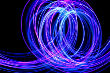 Long exposure photograph of neon blue streaks of light in an abstract swirl, parallel lines pattern against a black background. Light painting photography.