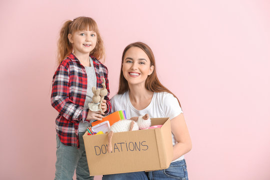 Volunteer with donations for orphans and little girl on color background