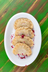 Dumplings with cherries. On a colored wooden background. Vegetarian dish.