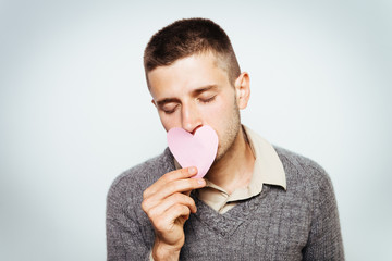 Portrait of a young man holding a large paper heart