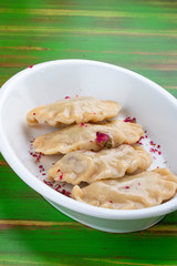 Dumplings with cherries. On a colored wooden background. Vegetarian dish.