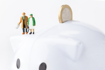 two miniature old men on a piggy bank