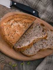 Sliced whole wheat bread on wooden board on planked table. Vertical shot from above.