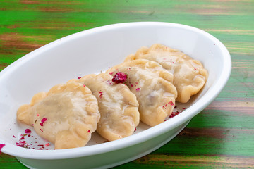 Dumplings with cherries. On a colored wooden background. Vegetarian dish.