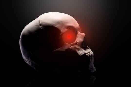 Model of the human skull with red eyes isolated on black background