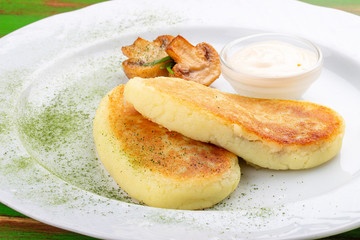 Potato zrazy with sour cream. On a colored wooden background. Vegetarian dish.
