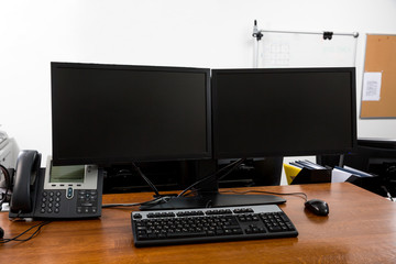 Workstation in modern office interior with dual black monitors on wooden desk close up