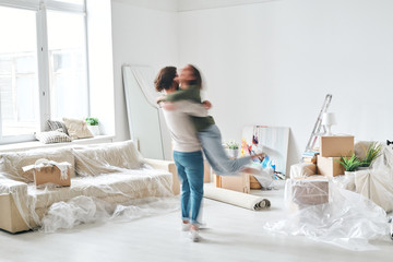 Blurry outline of young man whirling his happy wife in the center of living-room