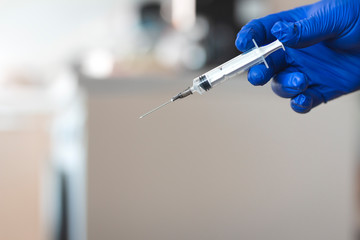 hand with surgical glove holding a syringe