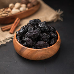 dried fruit in a square wooden bowl on a dark background and burlap