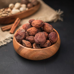 dried fruit in a square wooden bowl on a dark background and burlap