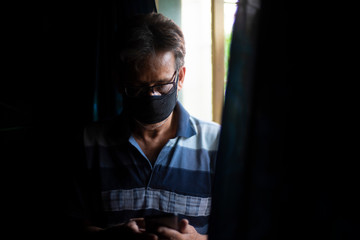 Portrait of an Indian old man wearing corona preventive mask in home isolation in front of a window. Indian lifestyle and disease.