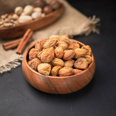 dried fruit in a square wooden bowl on a dark background and burlap