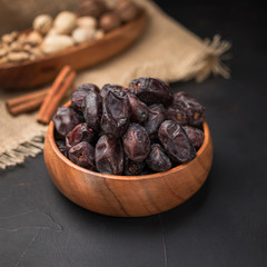 dried fruit in a square wooden bowl on a dark background and burlap