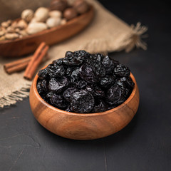 dried fruit in a square wooden bowl on a dark background and burlap