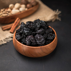 dried fruit in a square wooden bowl on a dark background and burlap