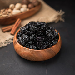 dried fruit in a square wooden bowl on a dark background and burlap