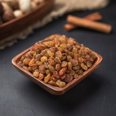 dried fruit in a square wooden bowl on a dark background and burlap