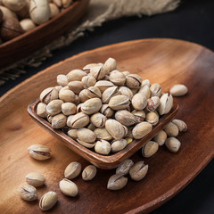 nuts on a square wooden bowl and an oval wooden tray on a dark background and burlap