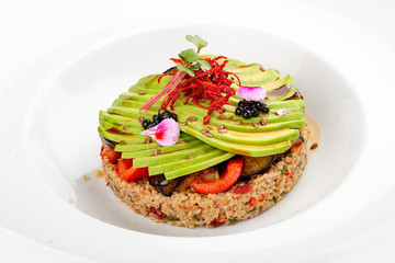 Salad with quinoa, avocado and roasted vegetables.  On a colored wooden background. Vegetarian dish.