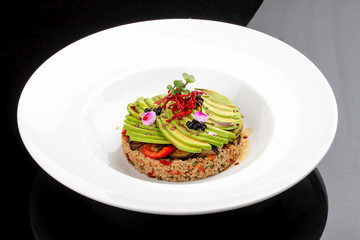 Salad with quinoa, avocado and roasted vegetables.  On a colored wooden background. Vegetarian dish.