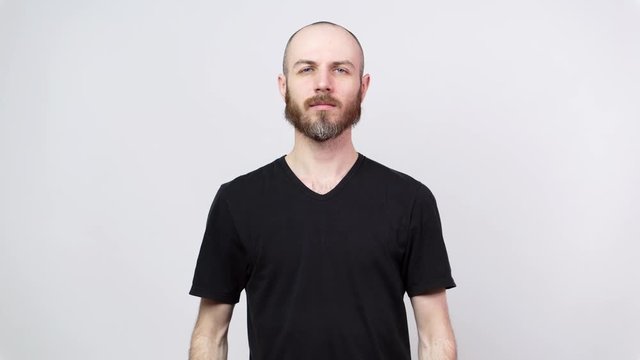 Portrait of calm bearded man looking at camera isolated over white background. Emotionless posing.