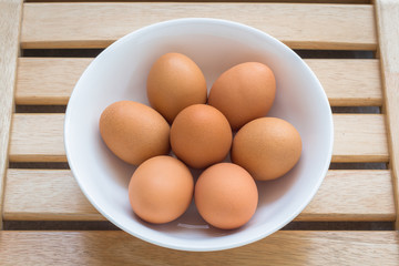 Eggs with brown shells in ceramic bowl on a brown wooden table