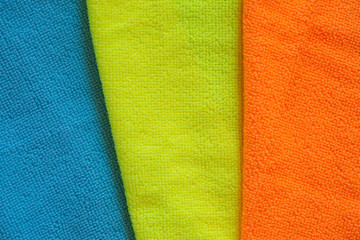 The concept of cleaning and washing. Mix of colored microfiber rags for cleaning on a blue background.