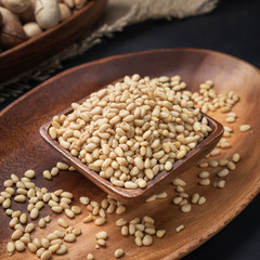 nuts on a square wooden bowl and an oval wooden tray on a dark background and burlap