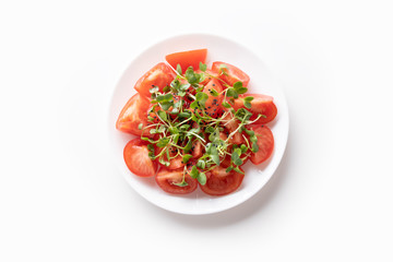 Fresh salad with tomatoes and micro green radishes on white. Top view. Concept vegan and healthy eating.