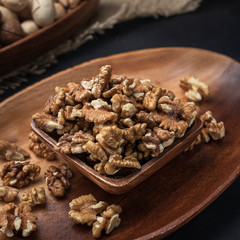 nuts on a square wooden bowl and an oval wooden tray on a dark background and burlap
