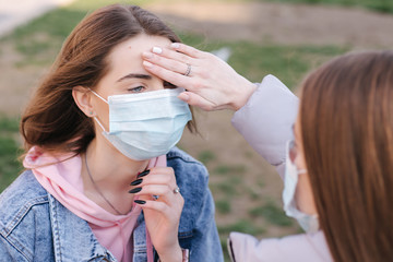 Obraz premium Woman in mask. Coronavirus theme. Women in the city measures temperature with a hand