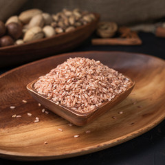 cereals and grains on a square wooden bowl and oval wooden tray on a dark background and burlap
