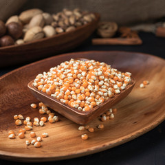 cereals and grains on a square wooden bowl and oval wooden tray on a dark background and burlap